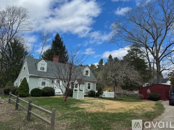 A house with a white fence and a red shed in the yard.