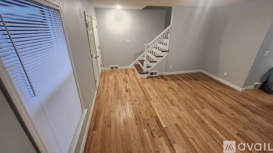 A room with wooden flooring and a staircase.