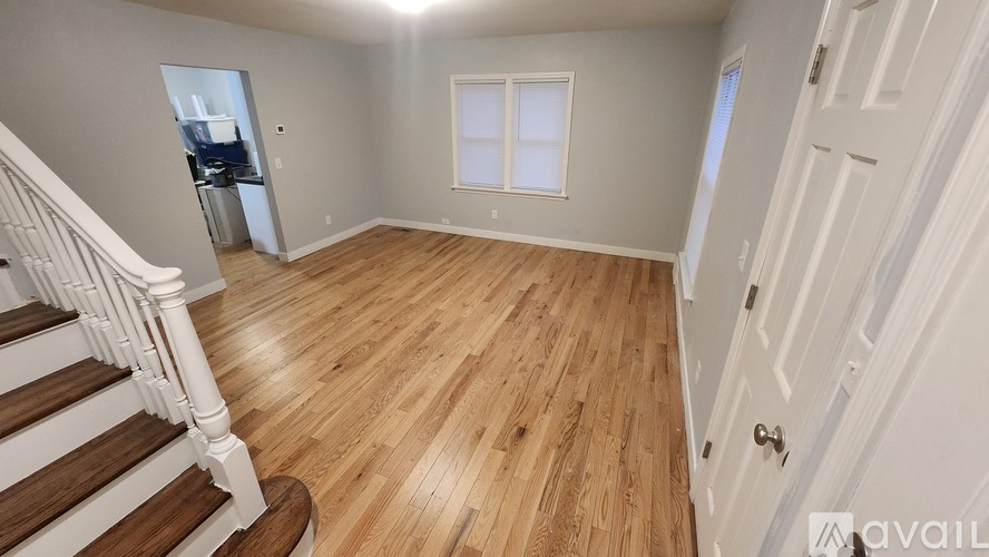 A room with wooden flooring and a staircase leading to another room.