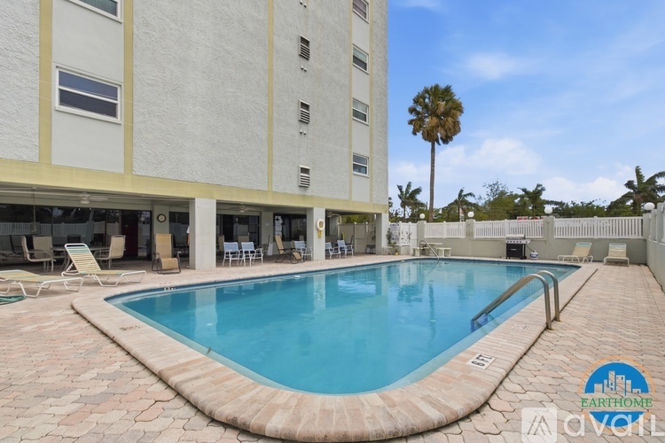A swimming pool in front of a building with a palm tree in the background.