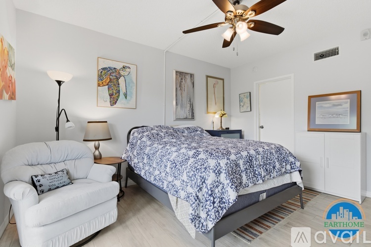 A bedroom with a bed, a chair, and a ceiling fan.