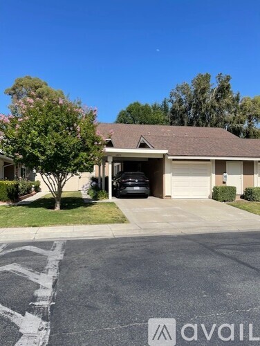 A house with a garage and a tree in front.