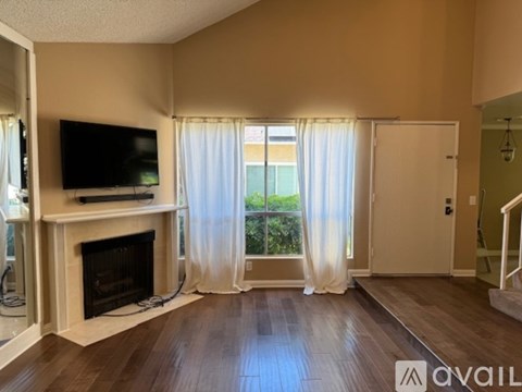 A living room with a fireplace and a television on the wall.