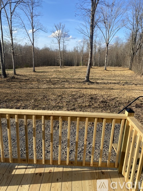 A wooden deck overlooks a field with trees.