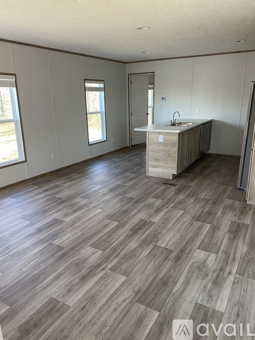 A room with wooden flooring and a kitchenette.