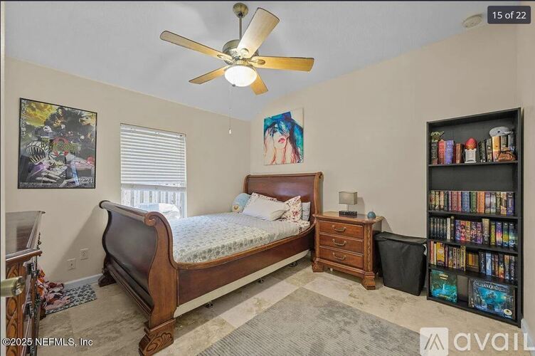 A bedroom with a bed, a ceiling fan, a bookshelf, and a painting on the wall.