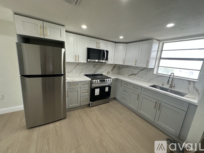 A kitchen with a stainless steel refrigerator, a microwave, a stove, and a sink.