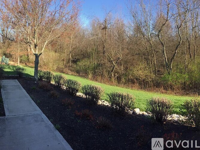 A pathway leads through a grassy area with trees and shrubs.