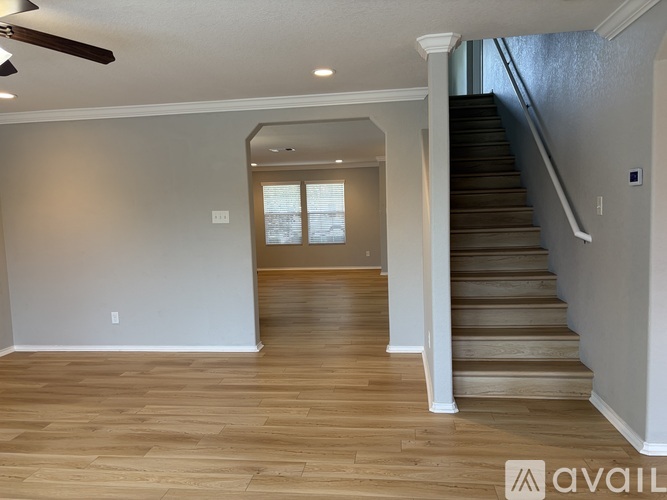 A spacious room with wooden flooring and a staircase leading to another level.