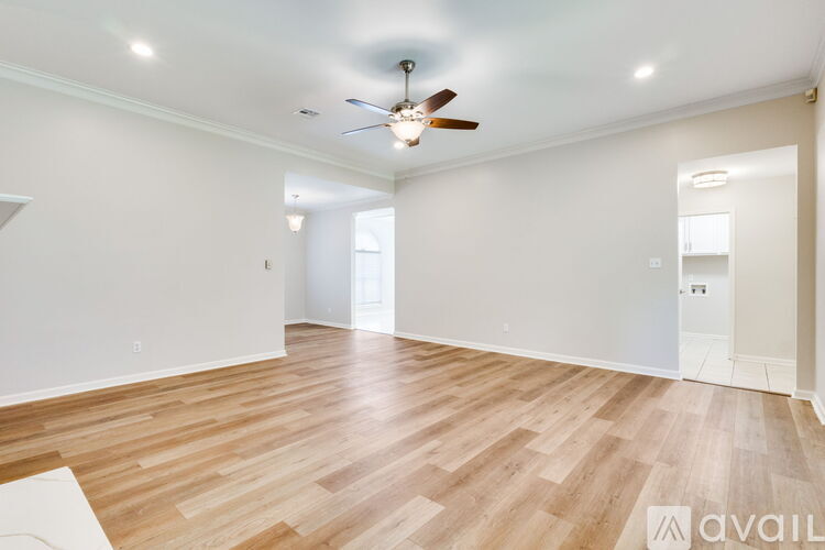 A spacious room with wooden flooring and a ceiling fan.