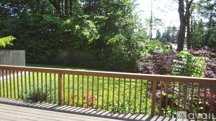 A wooden deck with a railing overlooking a lush green garden.