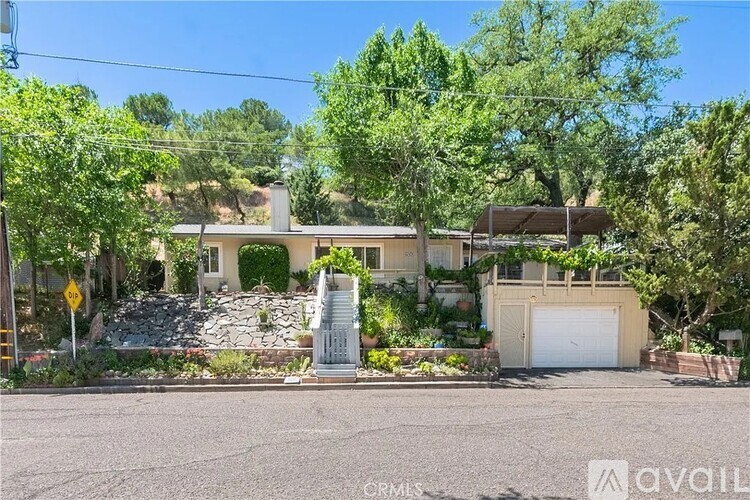 A house with a stone wall and a garage door is for sale.