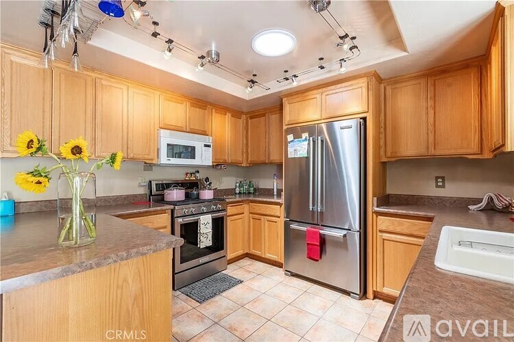 A kitchen with wooden cabinets and a stainless steel refrigerator.