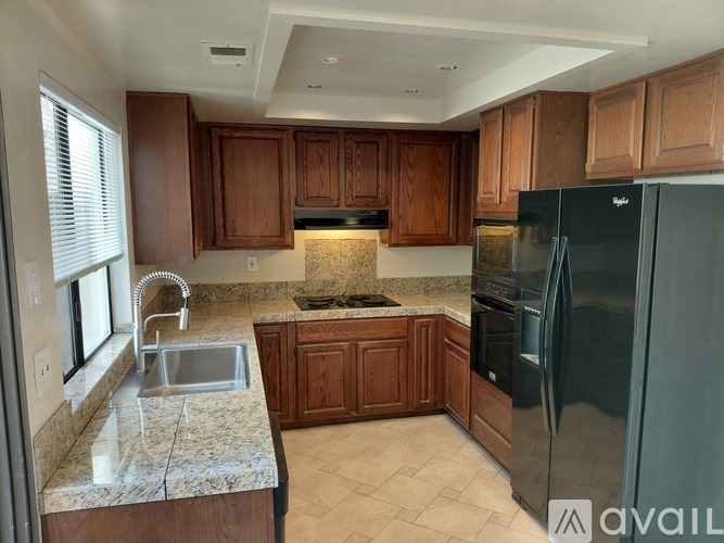 A kitchen with wooden cabinets and a black refrigerator.
