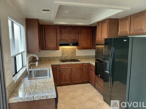 A kitchen with wooden cabinets and a black refrigerator.