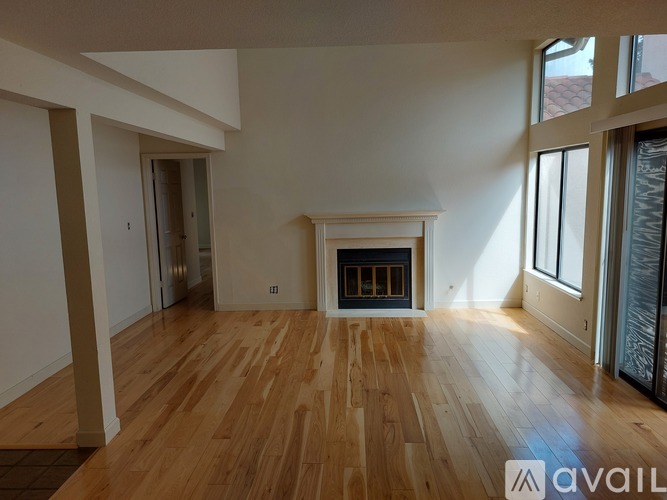 A spacious room with a fireplace and wooden flooring.