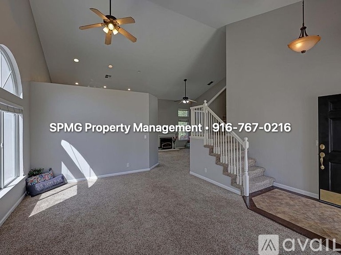 A living room with a carpeted floor and a ceiling fan.