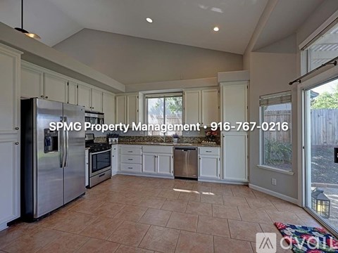 A kitchen with a refrigerator, oven, and cabinets with a phone number for SPMG Property Management.