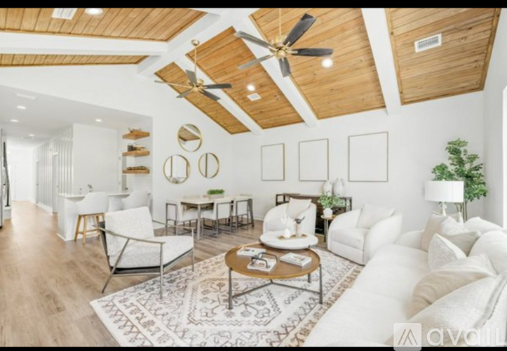 A living room with white furniture and a wooden ceiling.