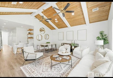A living room with white furniture and a wooden ceiling.