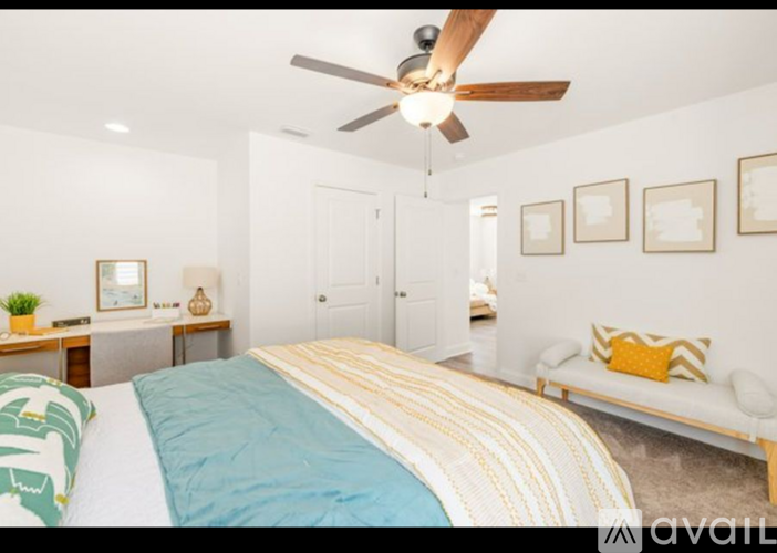 A bedroom with a bed, a bench, and a ceiling fan.