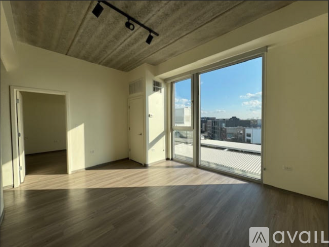A room with wooden floors and a sliding glass door leading to a balcony.