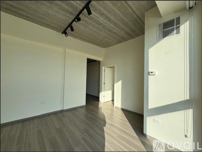 A room with a wooden floor and a white wall with a door.