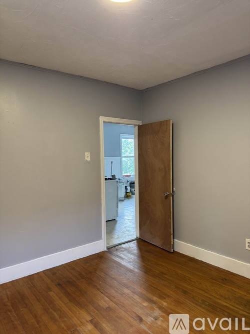 A room with a wooden floor and a door leading to a balcony.