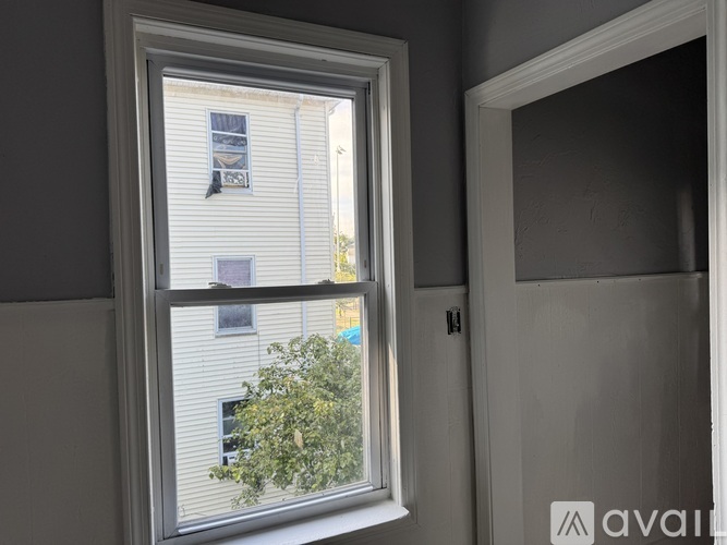 A window with a view of a building and a tree outside.