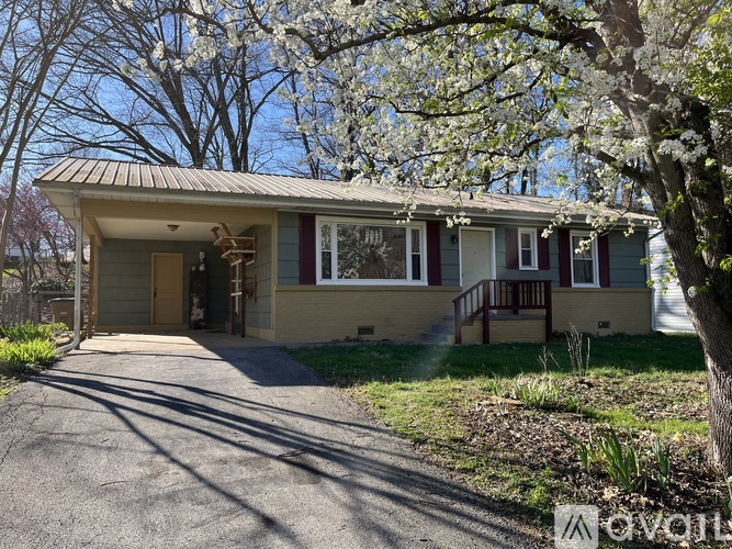 A house with a driveway and trees in bloom.