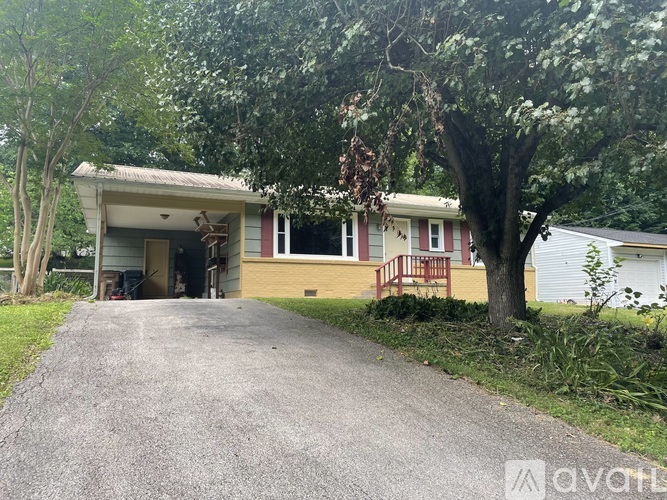 A house with a driveway and trees in front.