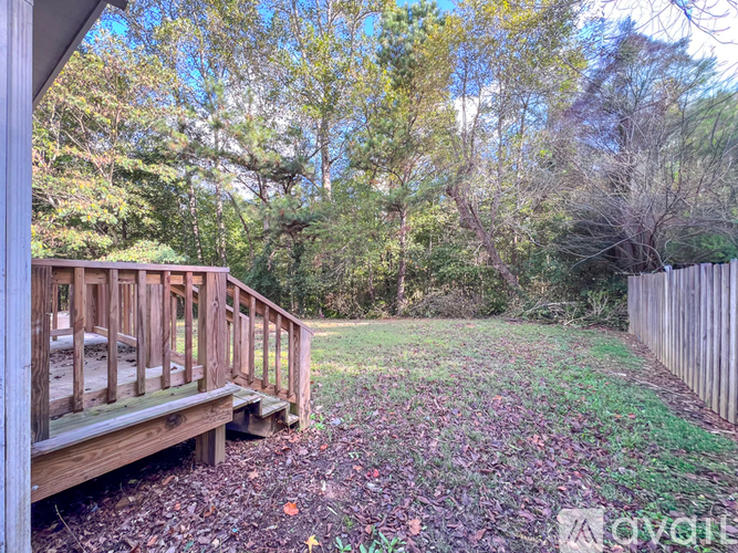 A wooden deck overlooks a grassy area with trees in the background.