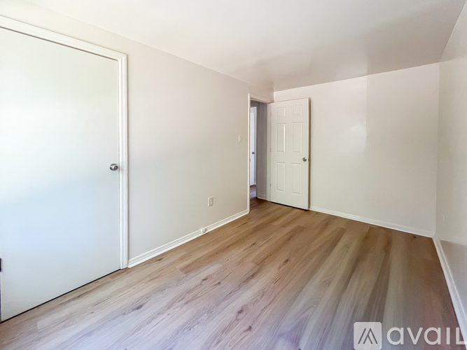 A room with white walls and wooden flooring with two doors.