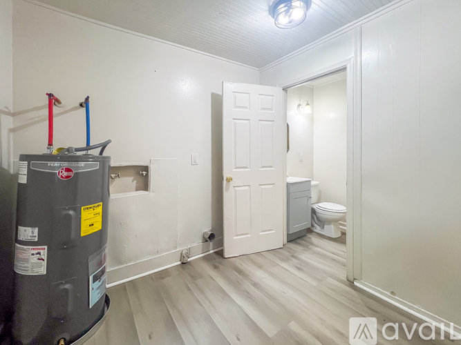 A room with a white door, a toilet, and a fridge.