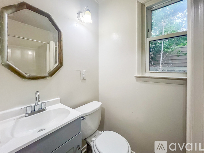A bathroom with a white sink, toilet, and a mirror.