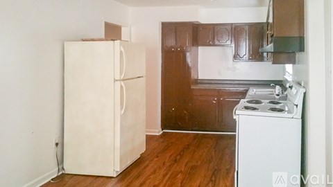 A white fridge and stove in a kitchen with wooden floors.
