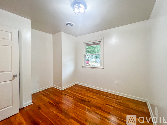 A room with wooden floors and a window showing greenery outside.