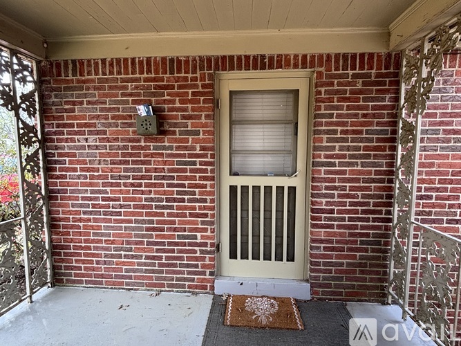 A red brick house with a white door and a brown doormat.