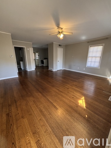 A spacious room with wooden floors and a ceiling fan.
