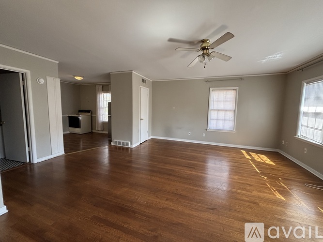 A spacious room with wooden floors and a ceiling fan.