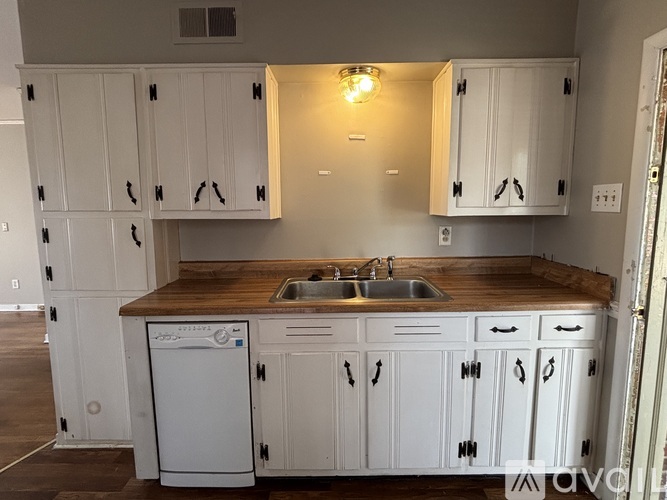 A kitchen with white cabinets and a wooden countertop.