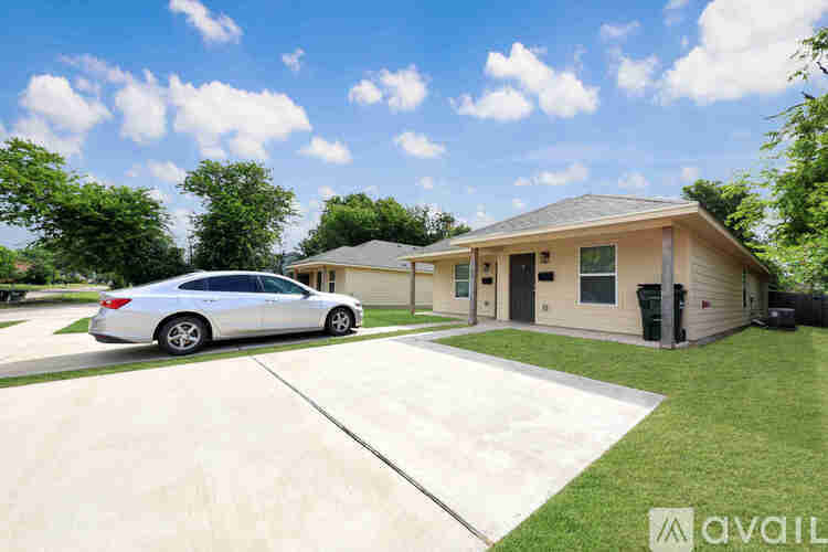 A silver car is parked in front of a house with a garage.