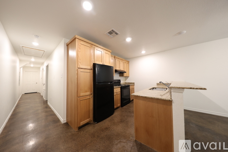 A kitchen area with wooden cabinets and a black refrigerator.