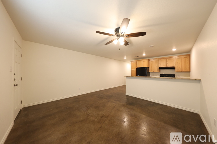 A room with a ceiling fan and brown flooring.