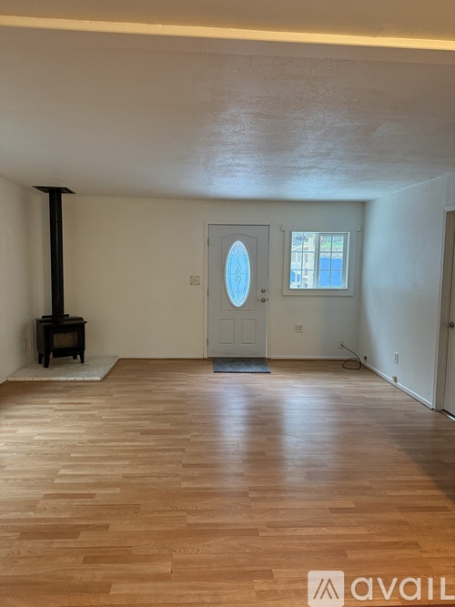 A room with a wood floor and a door with a round window.