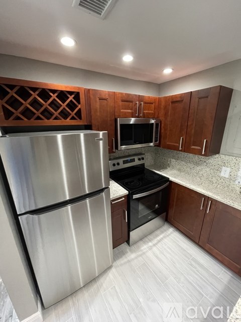 A kitchen with a stainless steel refrigerator and wooden cabinets.