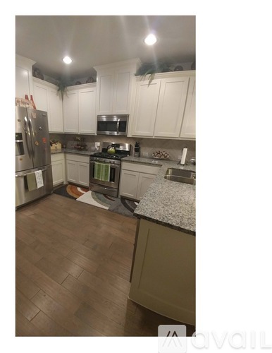 A kitchen with white cabinets and a wooden floor.