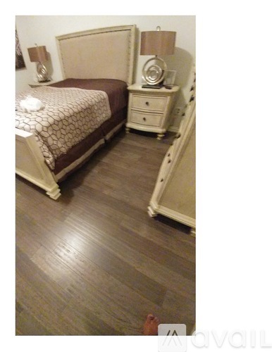 A bedroom with a bed, nightstand, and lamp.