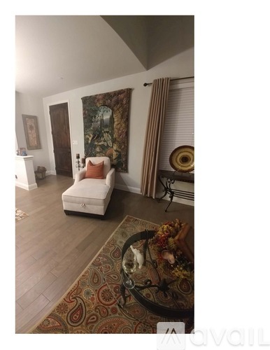 A living room with a white chair and a large tapestry hanging on the wall.