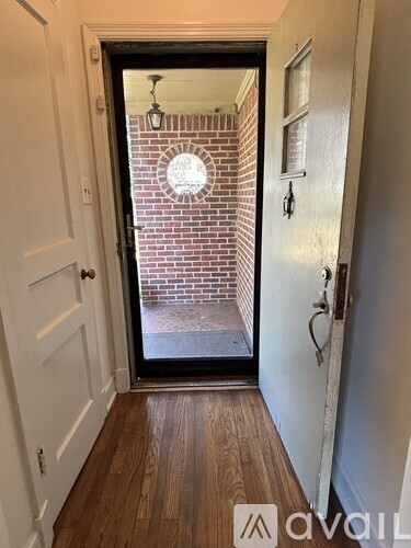 A hallway with a door leading to a brick wall.